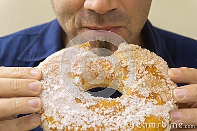 Man bite huge doughnut in his hands, sugar on his face Stock Photo