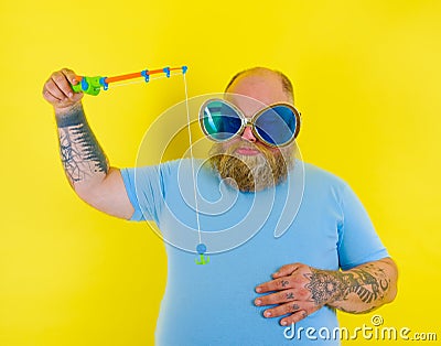 Fat man with beard and sunglasses is unhappy with the fishing rod Stock Photo