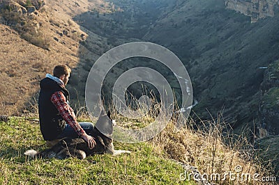 A man with a beard walking his dog in the nature, standing with a backlight at the rising sun, casting a warm glow and Stock Photo