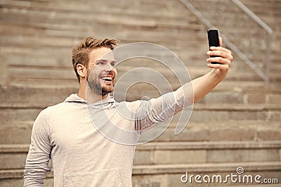 Man with beard walks with smartphone, urban background with stairs. Man blogger using video conferencing on smartphone Stock Photo