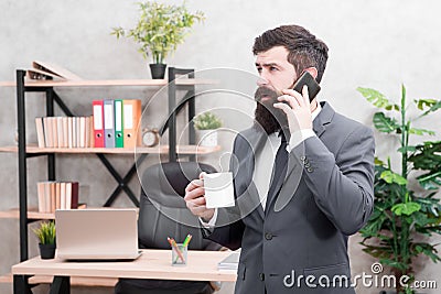 Man bearded businessman hold cup and smartphone. Coffee is pledge of successful negotiations. Caffeine addicted. Mobile Stock Photo