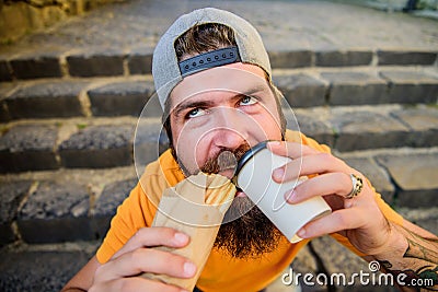 Man bearded eat tasty sausage. Urban lifestyle nutrition. Junk food. Carefree hipster eat junk food while sit stairs Stock Photo