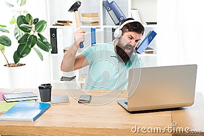 Man bearded guy headphones office swing hammer on computer. Slow internet connection. Outdated software. Computer lag Stock Photo