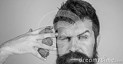 Man bearded hipster hold hand with strawberries near face. Man can not think about anything but strawberry blue Stock Photo