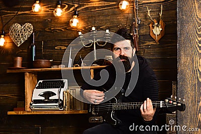 Man bearded musician enjoy evening with bass guitar, wooden background. Soul music. Man with beard holds black electric Stock Photo