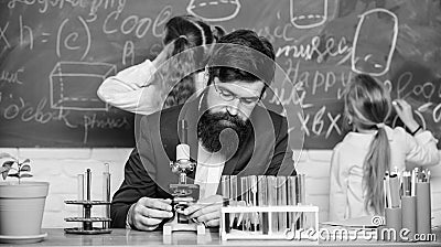 Man bearded teacher work with microscope and test tubes in biology classroom. Explaining biology to children. Biology Stock Photo