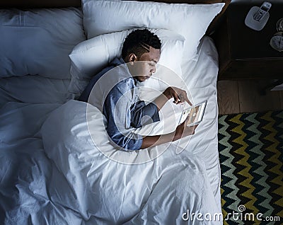 Man in bed using a digital device in the dark Stock Photo