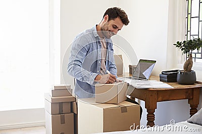 Man In Bedroom Running Business From Home Labeling Goods Stock Photo