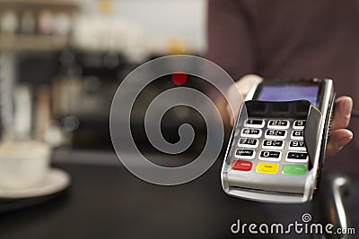 Man behind cafe counter offers credit card reader, close up Stock Photo