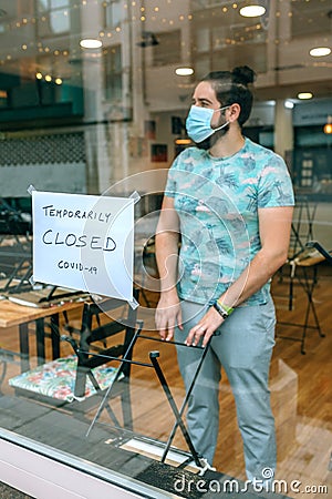 Man behind the glass of his restaurant closed by covid-19 Stock Photo
