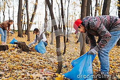 Man bending over, picking up trash in a seasonal forest at autumn Stock Photo