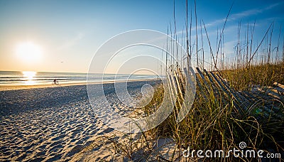 Man on a bicycle riding on the beach at sunrise Stock Photo