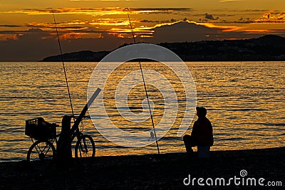 Man, fishing on the coast at sunset. Silhouette. Stock Photo