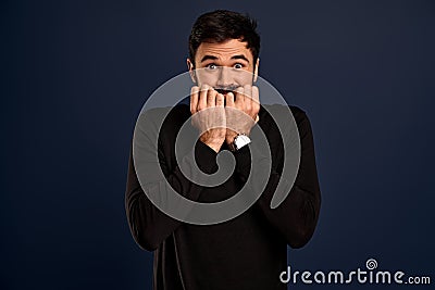 Man biting his nails as feeling nervous and scared wife find out. Anxious, troubled panicking hansome guy in casual outfit, hold Stock Photo