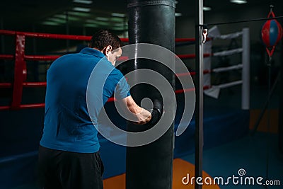 Man in black handwraps exercises with bag in gym Stock Photo