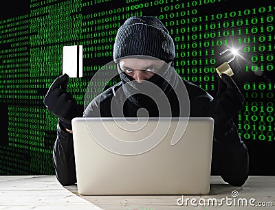 Man in black holding credit card and lock using computer laptop for criminal activity hacking bank account password Stock Photo