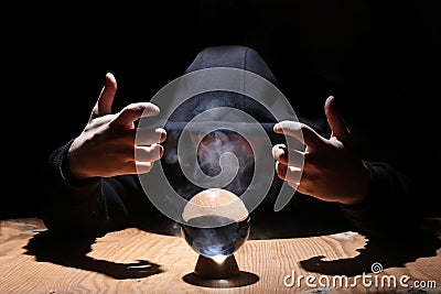 Man in a black hood with cristal ball Stock Photo