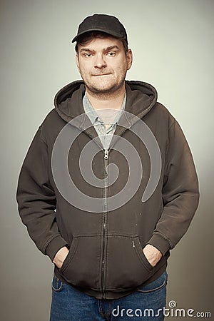 Rowdy bad man in black hooded shirt and black hat posing in studio Stock Photo