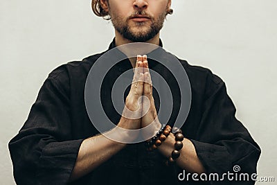 A man in black shirt sitting folded palms together, doing yoga. Hands folded in prayer. Hands together. Yoga. qigong Stock Photo