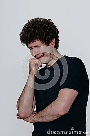 A man in a black T-shirt is very unhappy, conveys the emotion of grief and despair Stock Photo