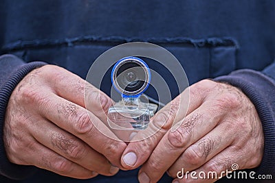 a man in blue clothes holds a small webcam Stock Photo