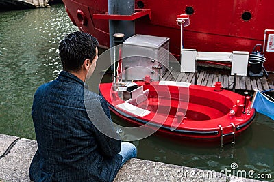 Man in blue jacket looking at Red Hot Tag with melted stove in Rotterdam. The hot tub concept in a floating wood-fired Editorial Stock Photo