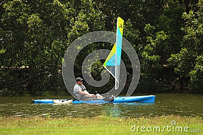 man on a blue peddle kayak with a small sail. Editorial Stock Photo