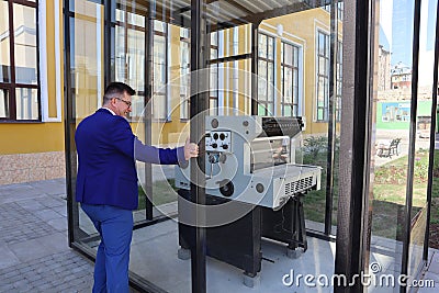 Man in a blue suit looks at the printing press behind the glass Stock Photo