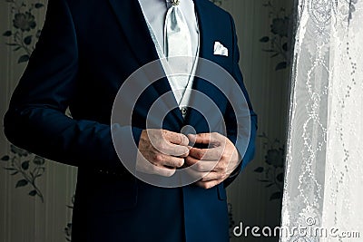 A man in a blue suit straightens his sleeves Stock Photo