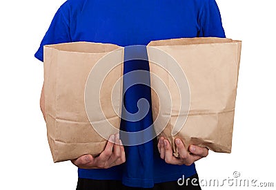 A man in a blue T-shirt holds two paper bags with groceries a white background. Social concept. Eco-friendly food delivery Stock Photo