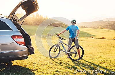 Man came by auto in mountain with his bicycle take it off and staying and enjoying landscape. Mountain biking concept image Stock Photo