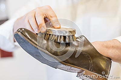 Man body and hand restoring parisian brown leather shoes. Stock Photo