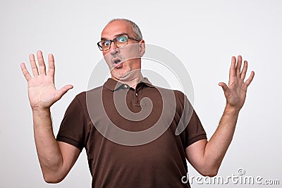 Man body language. I did not do it concept. Mature italian handsome man raising hands up. Stock Photo