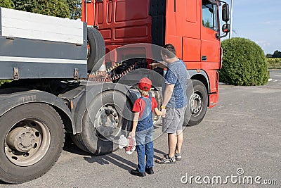 man and a boy, father and son, stand in front of a large truck, examining its mechanism Stock Photo