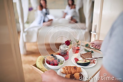 Young man bringing breakfast in bed for two female. lesbian, bisexual, threesome concept Stock Photo