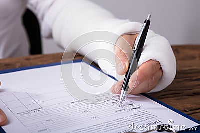 Man With Broken Arm Filling Health Insurance Claim Form Stock Photo