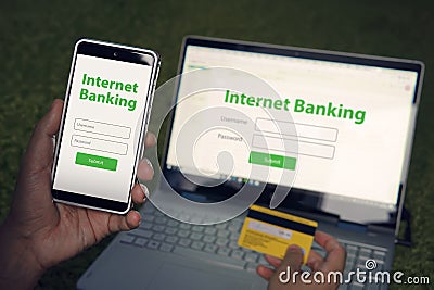 Man browsed homepage of internet banking service on his smartphone and laptop holding credit card. Online payment mobile Stock Photo