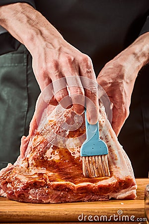 Man brushing beef ribs with marinade, close-up shot Stock Photo