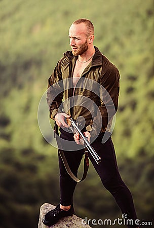 Man brutal poacher with weapon natural landscape background. Hunter poacher looking for victim. Hunter with rifle nature Stock Photo