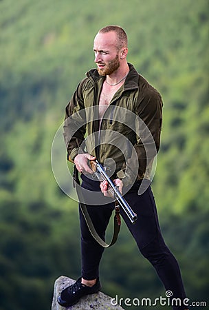 Man brutal poacher with weapon natural landscape background. Hunter poacher looking for victim. Hunter with rifle nature Stock Photo