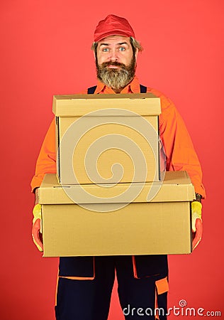 Man builder in boilersuit hold boxes. moving to new apartment. happy man cardboard box. carrying boxes inside the Stock Photo