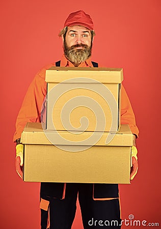 Man builder in boilersuit hold boxes. moving to new apartment. happy man cardboard box. carrying boxes inside the Stock Photo
