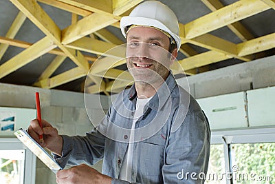 man in building helmet writing on clipboard Stock Photo