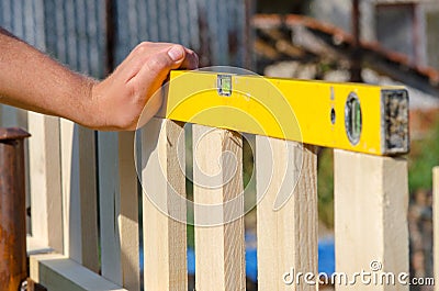 Man building a wooden fence and checking with spirit level. Close up of his hand and the tool in a DIY concept. Stock Photo