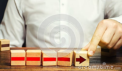 Man builds an arrow from blocks. Business development, growth process concept. Career promotion, improving skills. Business Stock Photo