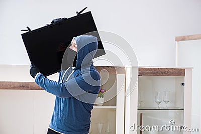 The man burglar stealing tv set from house Stock Photo