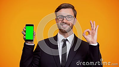 Man of business showing smartphone with green screen and ok gesture, cash-back Stock Photo