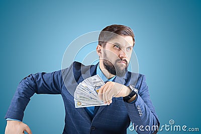 Man in a business suit with banknotes in his hands looks straight, a businessman with a fan of money looks with a tense look Stock Photo