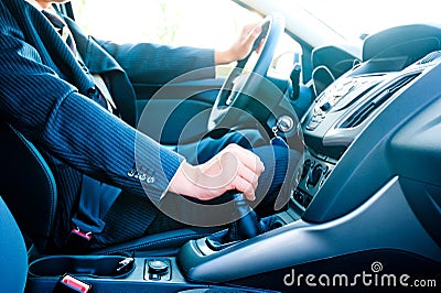 Man in a business suit in the car changes gear Stock Photo