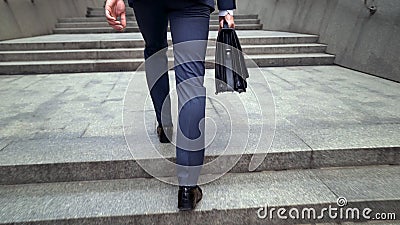 Man in business suit walking upstairs holding briefcase beginning of working day Stock Photo